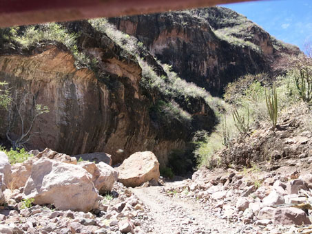 Road entering a narrow canyon with high steep rock walls